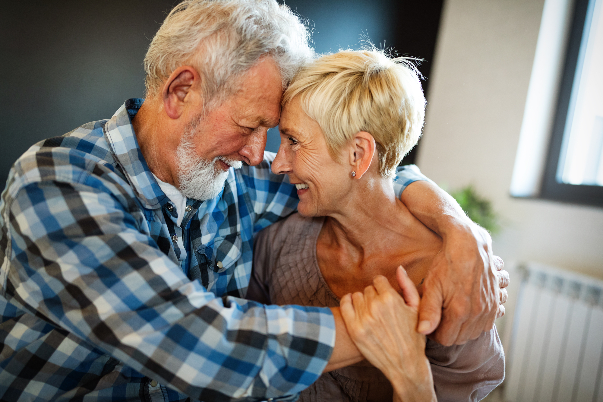 older woman and man hugging with foreheads touching